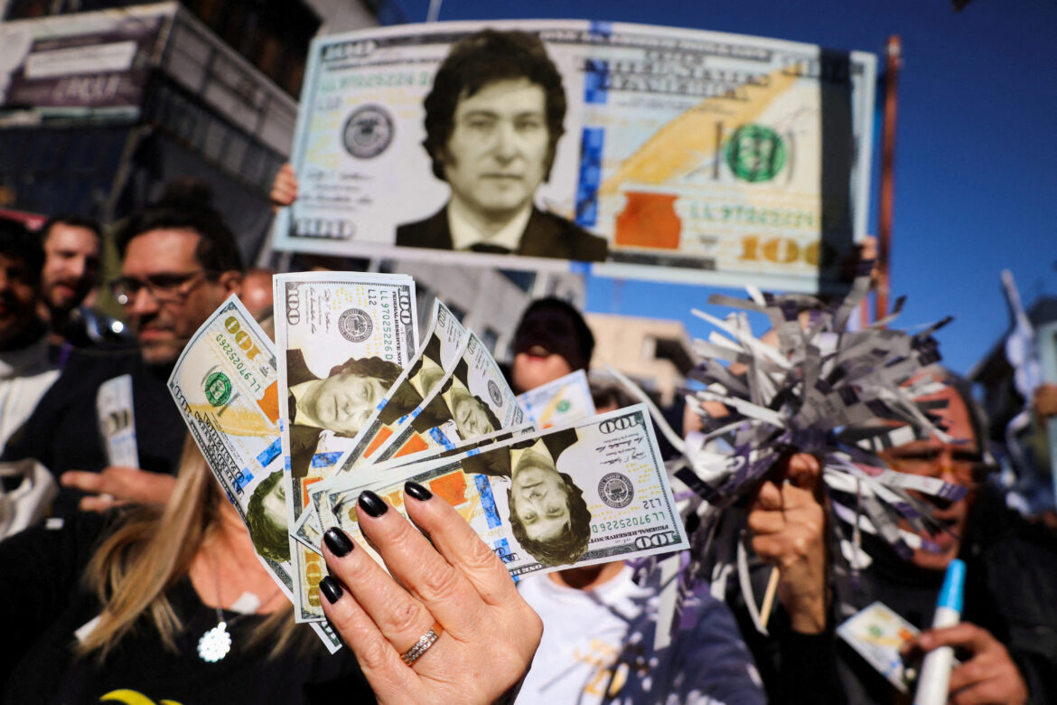 FILE PHOTO: Supporters of Argentine presidential candidate Javier Milei hold dollar bills with his face on them, during a campaign rally, in Buenos Aires, Argentina September 25, 2023. REUTERS/Cristina Sille//File Photo