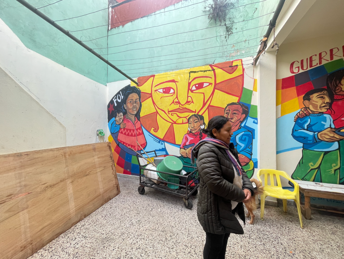 Ana standing in the backyard of Frente de Organizaciones en Lucha (FOL) in front of a mural. Image by Zoya Ahmer. Argentina, 2024.