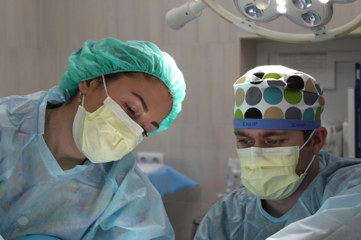 Doctors wear surgical masks and hairnets in a hospital. Photo: stock image by Pavel Sorokin via Pexels